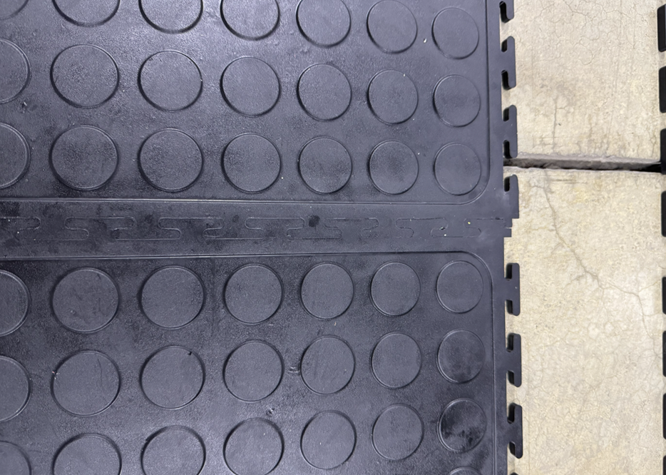 Close-up of black interlocking Dura Tiles installed over a concrete floor